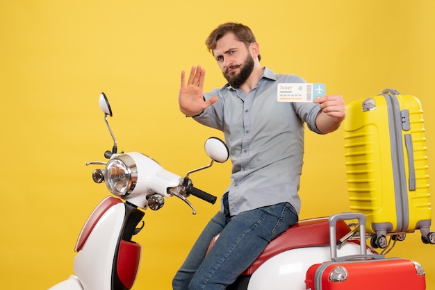 Concepto de viaje con joven barbudo emocional sentado en moto y mostrando cinco billetes de explotación en amarillo