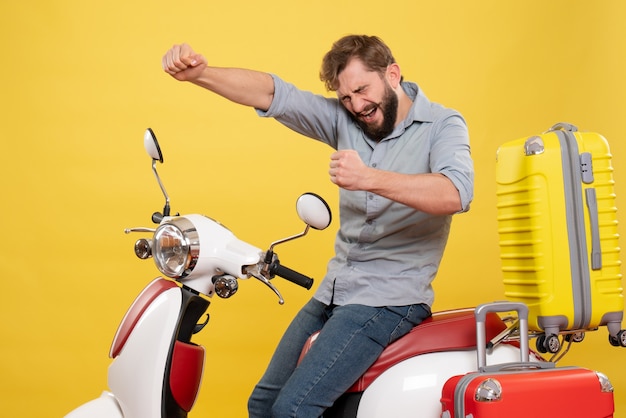Concepto de viaje con joven barbudo orgulloso sentado en la motocicleta y disfrutando de su éxito en amarillo