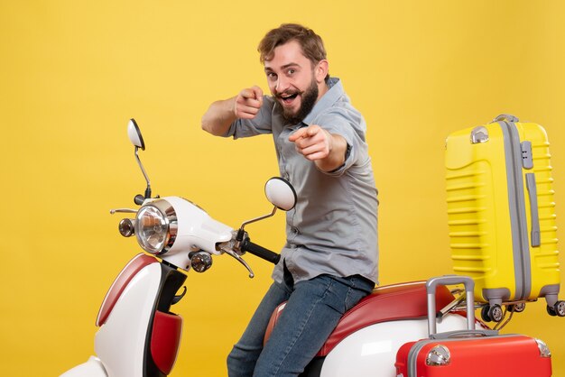 Concepto de viaje con joven barbudo sonriente sentado en moto y apuntando hacia adelante en amarillo