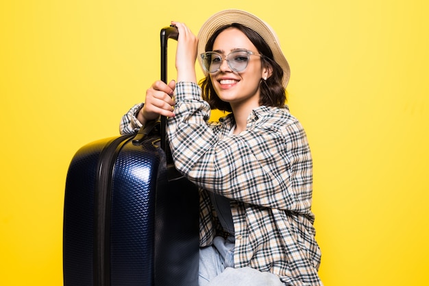 Concepto de viaje. Mujer turista feliz con sombrero y gafas de sol listo para viajar con maleta y pasaporte aislado.