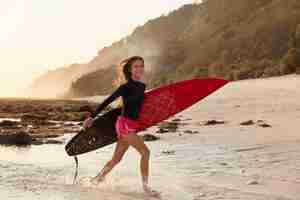 Foto gratuita concepto de viaje, recreación y pasatiempo. feliz adolescente en alto espíritu después de surfear