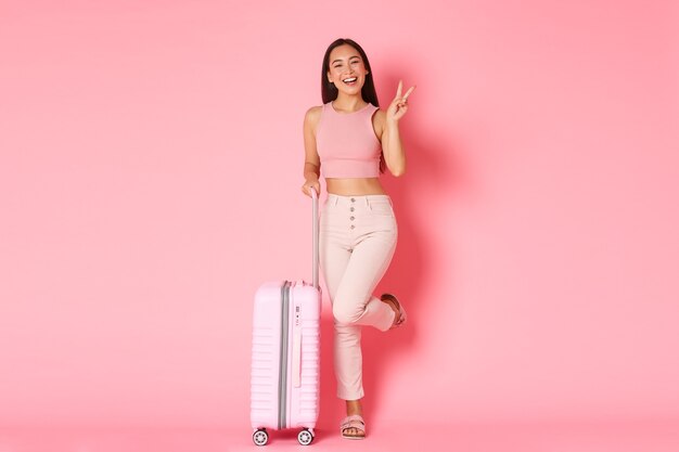 Concepto de viaje, vacaciones y vacaciones. Alegre chica asiática en ropa de verano llena de bolsas para viajar al extranjero