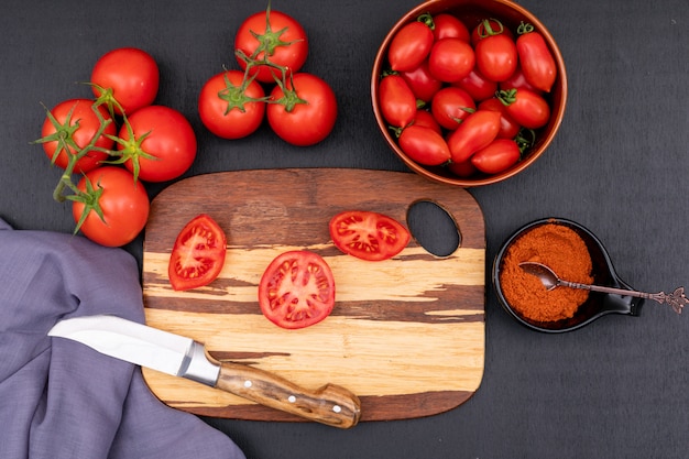 Concepto de vista superior de tomates con cuchillo en la tabla de cortar en la oscuridad