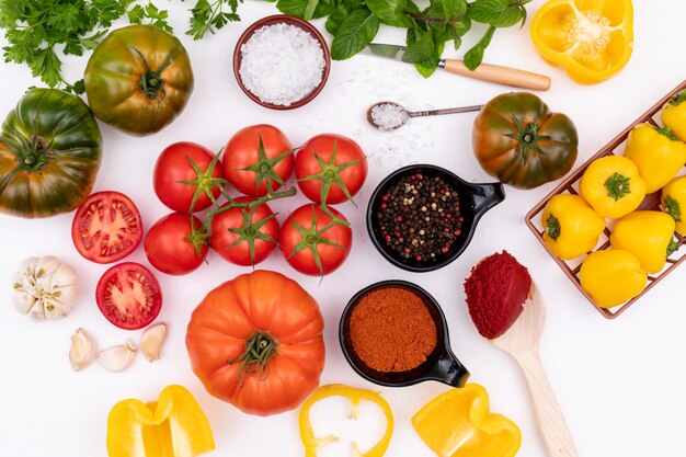 Concepto de vista superior de tomates con pimiento amarillo ajo y sal en superficie blanca