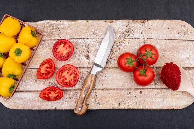 Concepto de vista superior de tomates en tabla de cortar con cuchillo y pimiento