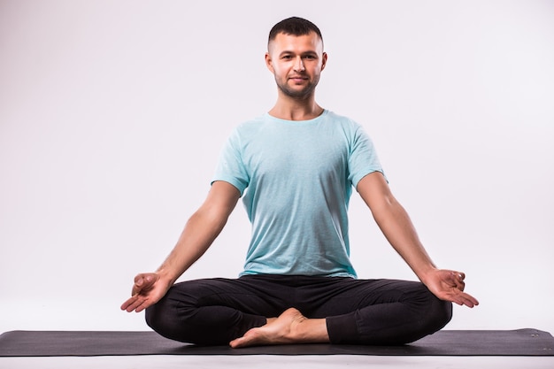 Concepto de yoga. Hombre guapo haciendo ejercicio de yoga aislado sobre un fondo blanco.