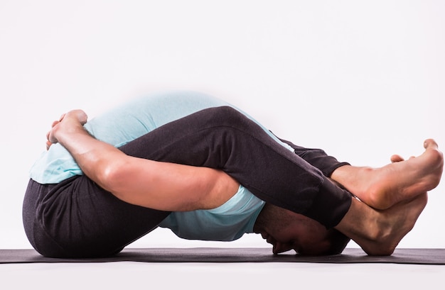 Concepto de yoga. Hombre guapo haciendo ejercicio de yoga aislado sobre un fondo blanco.