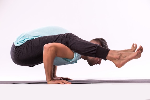 Foto gratuita concepto de yoga. hombre guapo haciendo ejercicio de yoga aislado sobre un fondo blanco.