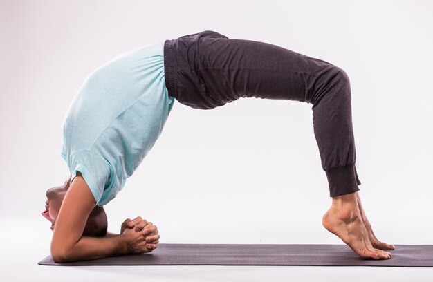 Concepto de yoga. Hombre guapo haciendo ejercicio de yoga aislado sobre un fondo blanco.