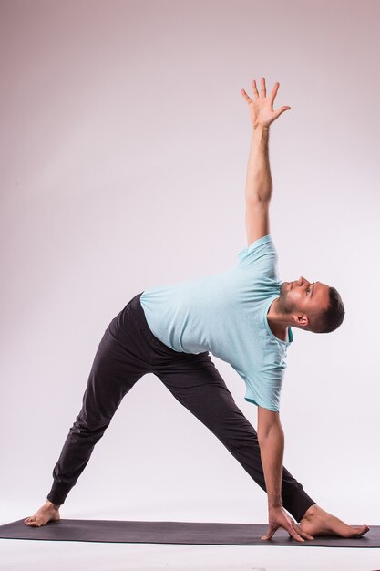 Concepto de yoga. Hombre guapo haciendo ejercicio de yoga aislado sobre un fondo blanco.