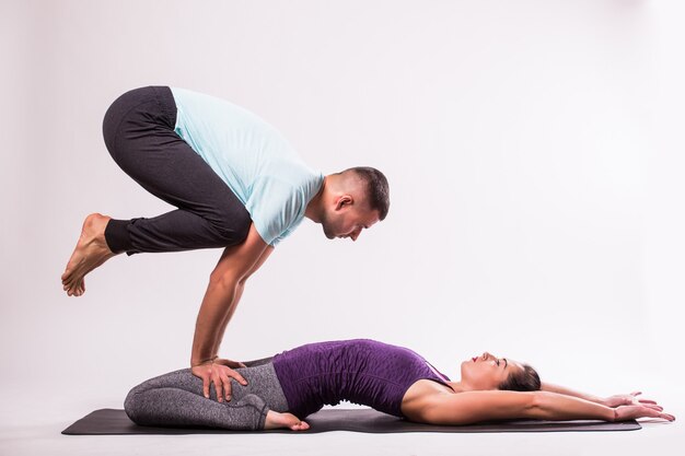 Concepto de yoga. Pareja joven sana en posición de yoga sobre fondo blanco.