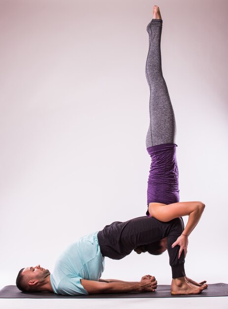 Concepto de yoga. Pareja joven sana en posición de yoga sobre fondo blanco.