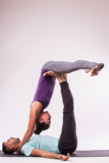 Concepto de yoga. Pareja joven sana en posición de yoga sobre fondo blanco.