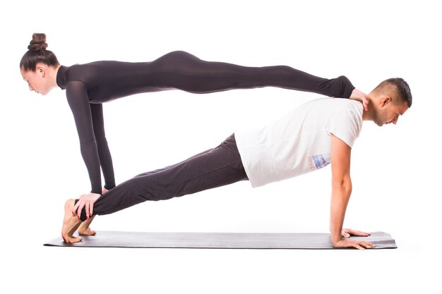 Concepto de yoga en pareja. Pareja joven sana en posición de yoga sobre fondo blanco.