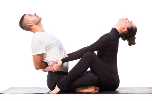 Concepto de yoga en pareja. Pareja joven sana en posición de yoga sobre fondo blanco.