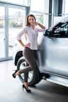 Foto gratuita concesionario de automóviles femenino posando junto al coche