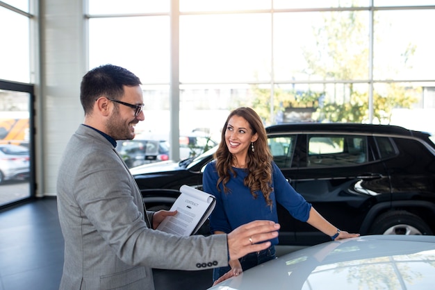 Concesionario de coches presentando coche nuevo al cliente