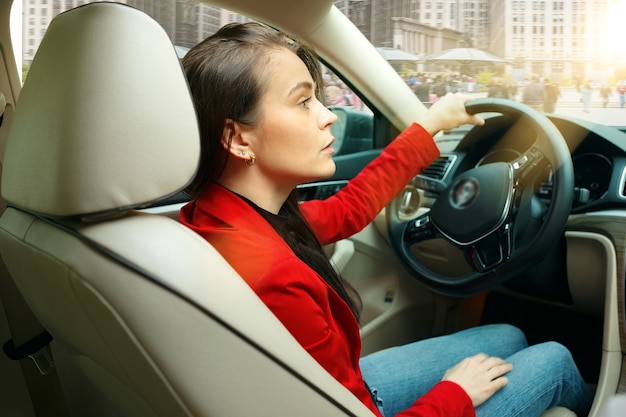 Conducir por la ciudad. Atractiva mujer joven conduciendo un coche