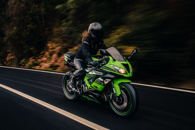 Conducir motocicleta verde en la carretera.