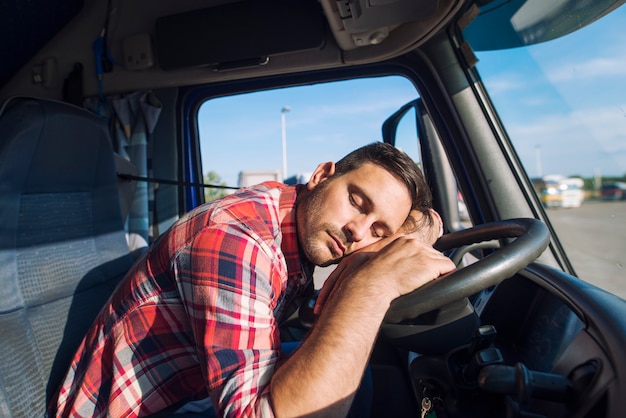 Conductor de camión agotado quedarse dormido en el volante