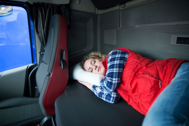 Conductor de camión cansado durmiendo en la cabina de su camión debido a la conducción de largas distancias y al exceso de trabajo