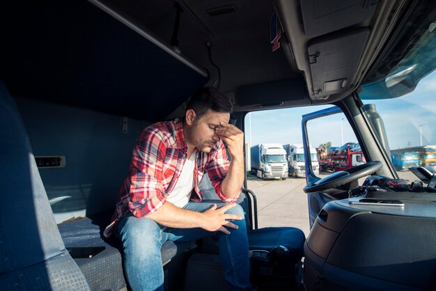 Conductor de camión sentado en la cabina de su camión sintiéndose preocupado y molesto