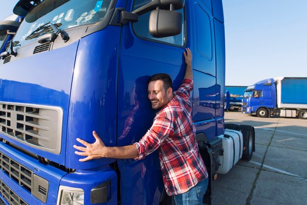 Conductor de camionero profesional abrazando la cabina de su camión amando su trabajo