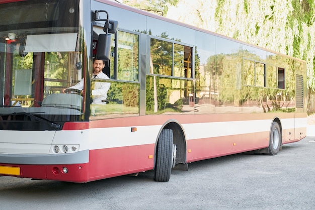 Foto gratuita conductor elegante sentado en el autobús sonriendo a la cámara en el día de verano vista frontal del hombre feliz