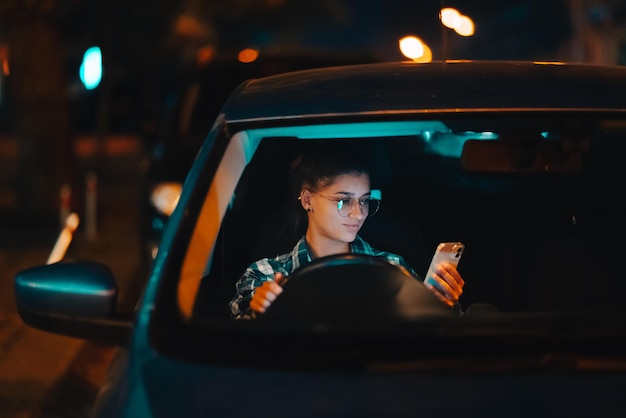 Conductor femenino perdido usando teléfono móvil mientras conduce de noche
