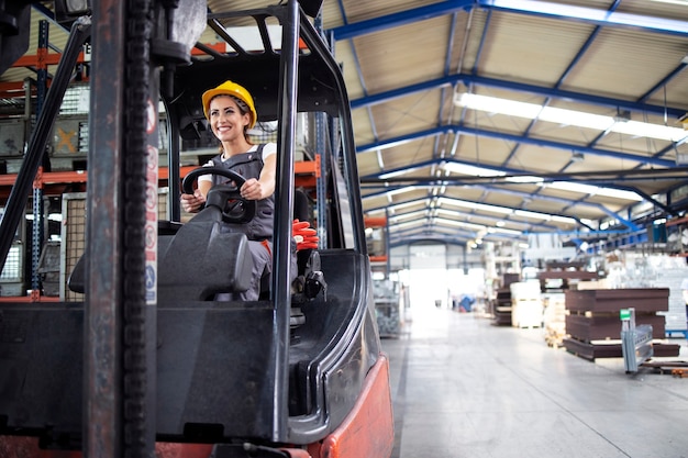 Foto gratuita conductor industrial femenino profesional operando la máquina de montacargas en el pasillo de la fábrica