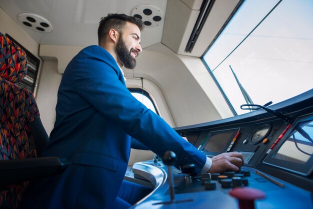 Conductor profesional sentado en la cabina y operando un tren de alta velocidad