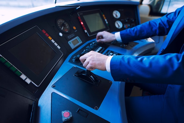 Conductor profesional en uniforme que opera en la cabina del tren y conduce un tren de alta velocidad