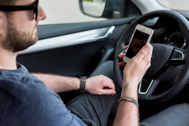 Conductor sosteniendo teléfono inteligente en el coche