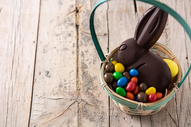 Conejito de chocolate de Pascua y huevos coloridos en la mesa de madera