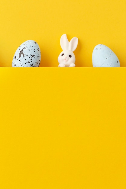 Conejito de Pascua con huevos sobre fondo amarillo con espacio de copia