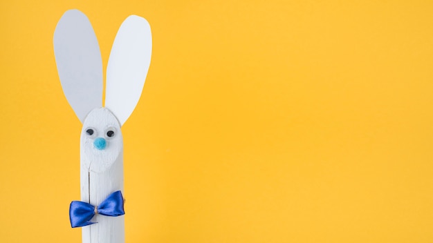 Foto gratuita conejo de madera con orejas de papel sobre fondo amarillo