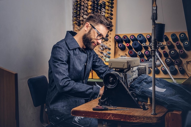 Confeccionando ropa "o" Fabricando ropa. sastre sentado a la mesa y trabajando en una máquina de coser en un taller de costura.