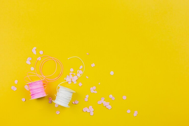 Foto gratuito confeti de papel con carrete rosa y blanco sobre fondo amarillo