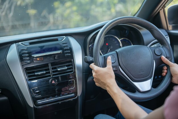 Confiado y hermoso. Vista trasera de una mujer joven atractiva en ropa casual mirando por encima del hombro mientras conduce un coche. chica sosteniendo la mano en la rueda para manejar el coche, concepto de seguridad.