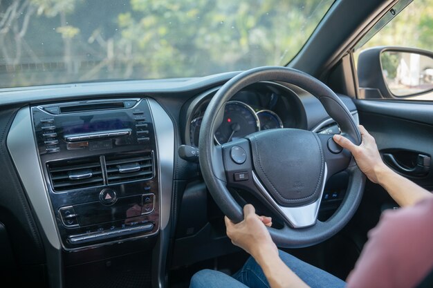 Confiado y hermoso. Vista trasera de una mujer joven atractiva en ropa casual mirando por encima del hombro mientras conduce un coche. chica sosteniendo la mano en la rueda para manejar el coche, concepto de seguridad.