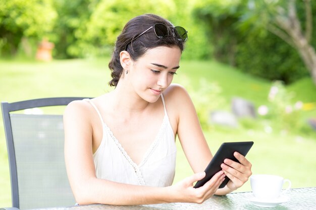 Confiamos en mujer joven utilizando tableta digital al aire libre