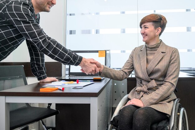 Confianza empresaria en silla de ruedas dándose la mano