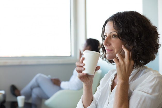 Confianza empresaria tomando café mientras habla por celular