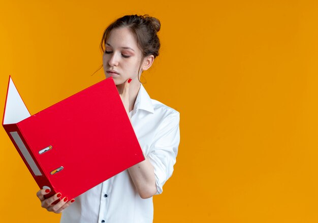 Foto gratuita confianza joven rubia rusa sostiene y mira la carpeta de archivos