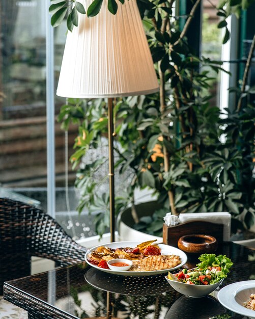 Configuración del almuerzo en el restaurante cerca de la ventana y la lámpara de pie