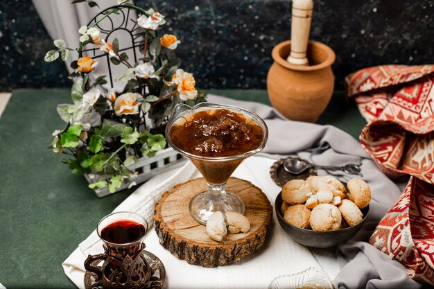 Confitura, galletas de mantequilla y un vaso de té.