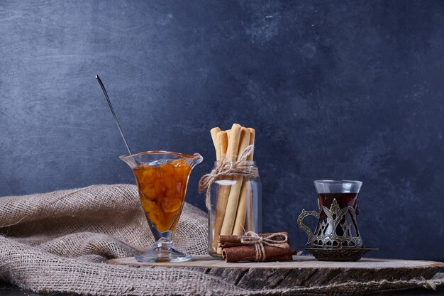 Confitura, palitos de gofre y un vaso de té.