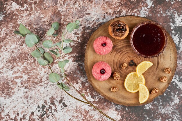 Confitura roja y galletas sobre una tabla de madera.