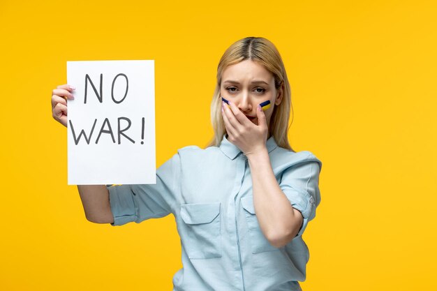 Conflicto ucraniano ruso linda chica fondo amarillo con bandera ucraniana en las mejillas llorando