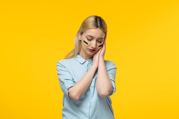 Conflicto ucraniano ruso linda chica fondo amarillo con bandera ucraniana en las mejillas tranquilas